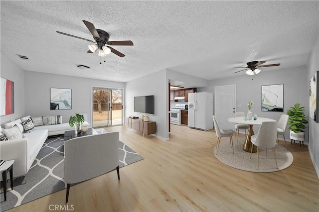 living room featuring ceiling fan, a textured ceiling, and light hardwood / wood-style flooring