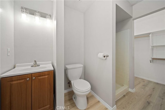 bathroom featuring a shower, vanity, wood-type flooring, and toilet