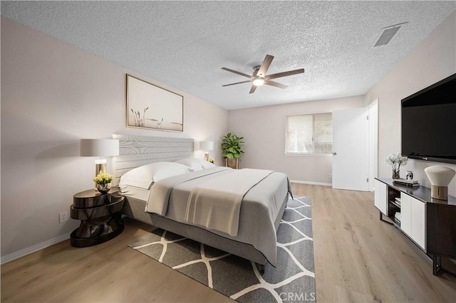 bedroom with a textured ceiling, light hardwood / wood-style floors, and ceiling fan