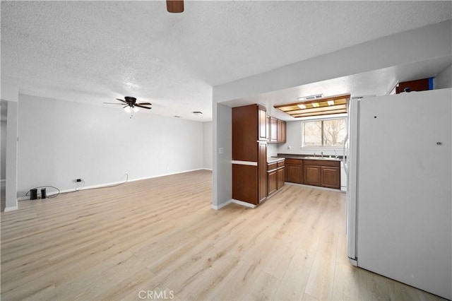 kitchen featuring a textured ceiling, white fridge, light hardwood / wood-style flooring, and ceiling fan