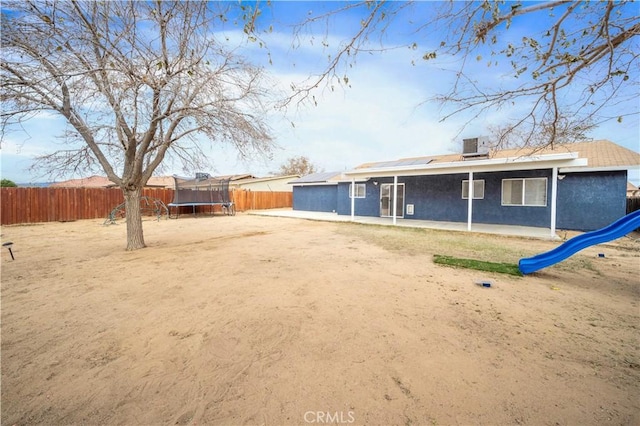 back of property featuring a playground and a trampoline