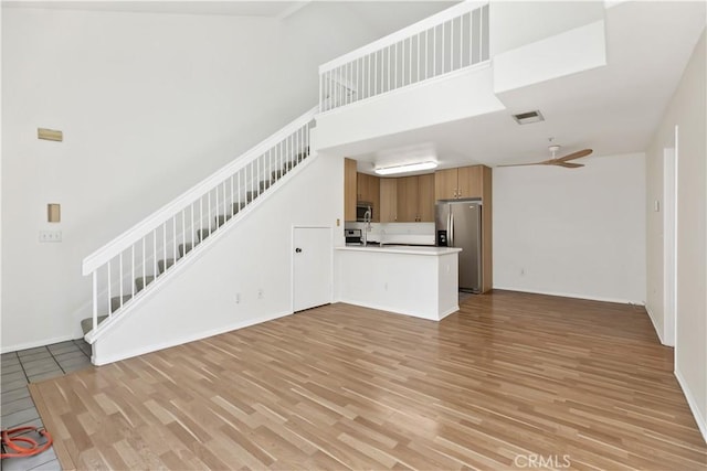 unfurnished living room with a high ceiling and light hardwood / wood-style flooring