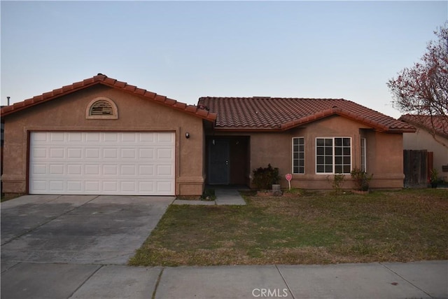 view of front facade featuring a tiled roof, a front yard, stucco siding, driveway, and an attached garage