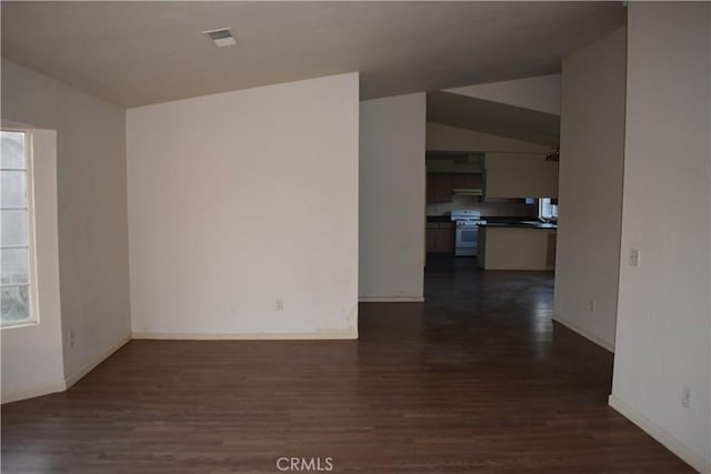 spare room featuring baseboards, lofted ceiling, and dark wood-style flooring