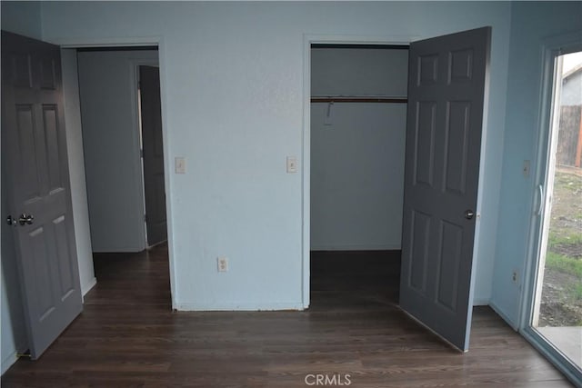 unfurnished bedroom with multiple windows, wood finished floors, and baseboards