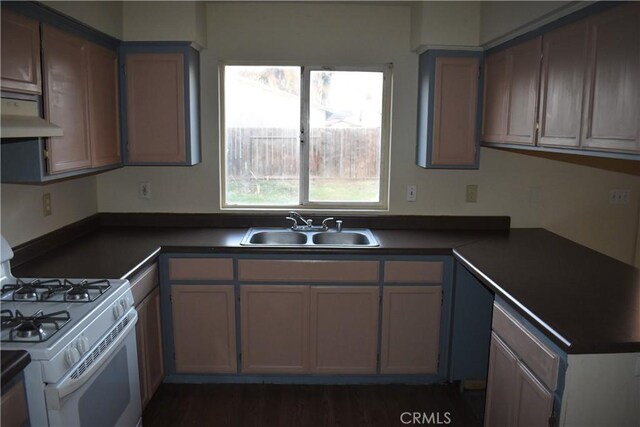 kitchen with white range with gas stovetop, dark hardwood / wood-style floors, extractor fan, and sink