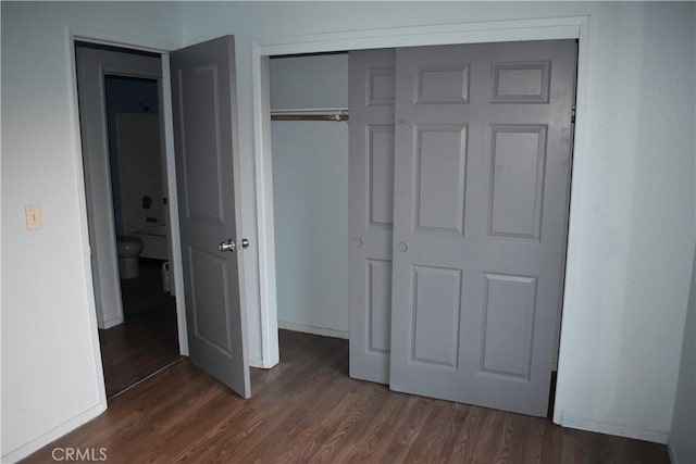 unfurnished bedroom featuring a closet and dark wood-type flooring