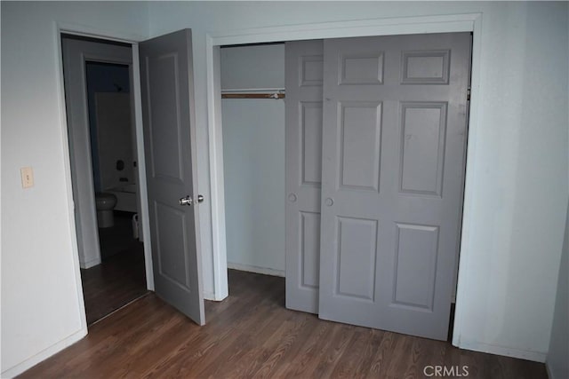 unfurnished bedroom featuring baseboards, dark wood-style flooring, and a closet