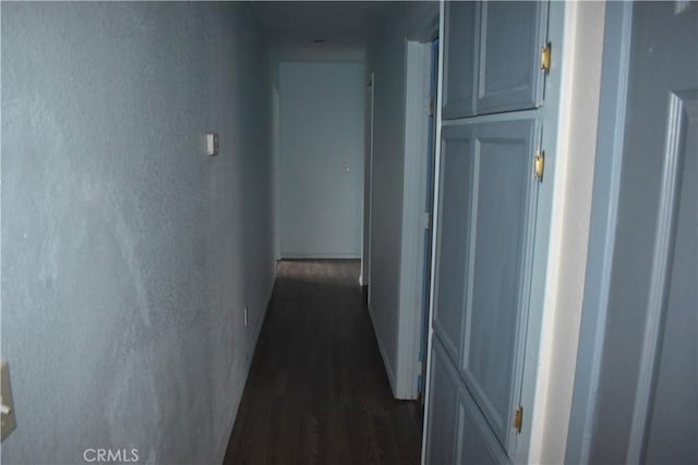 corridor with dark wood-style floors and a textured wall