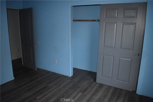 unfurnished bedroom with a closet and dark wood-type flooring