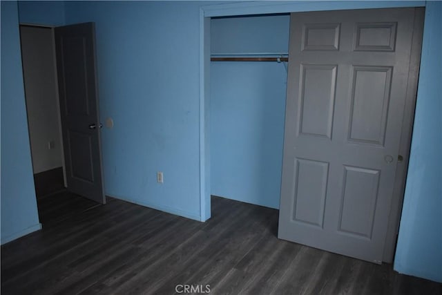 unfurnished bedroom featuring a closet and dark wood-style flooring