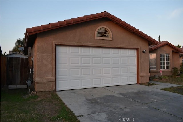 garage with concrete driveway and fence