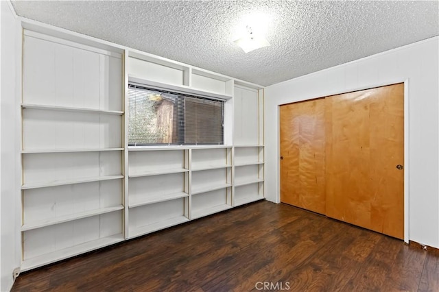 unfurnished bedroom featuring a textured ceiling, dark hardwood / wood-style flooring, and a closet