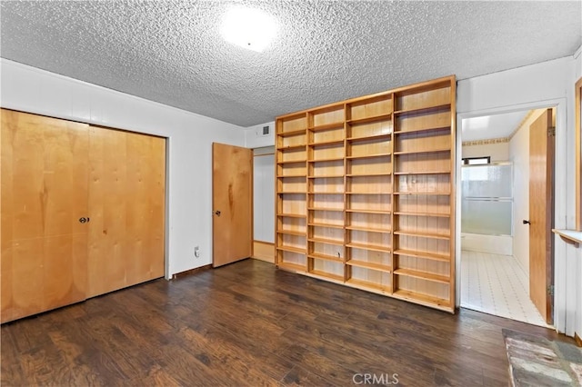 unfurnished bedroom with dark hardwood / wood-style flooring and a textured ceiling