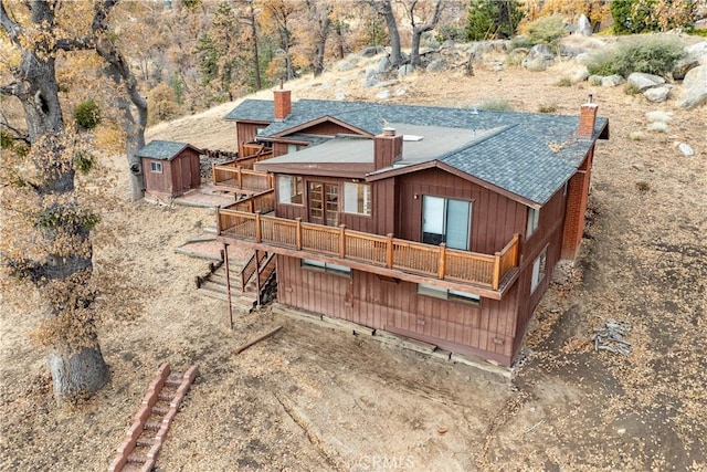 rear view of house featuring a shed and a wooden deck