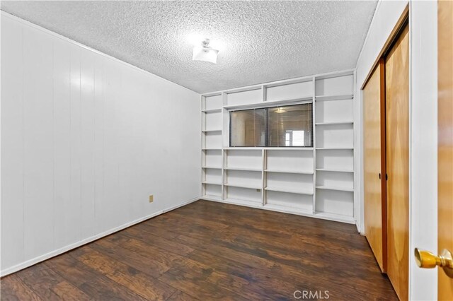 empty room featuring a textured ceiling and dark wood-type flooring