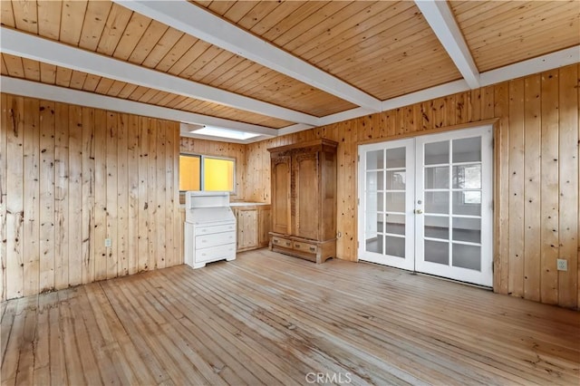 unfurnished room featuring wood walls, wooden ceiling, french doors, beamed ceiling, and light hardwood / wood-style floors