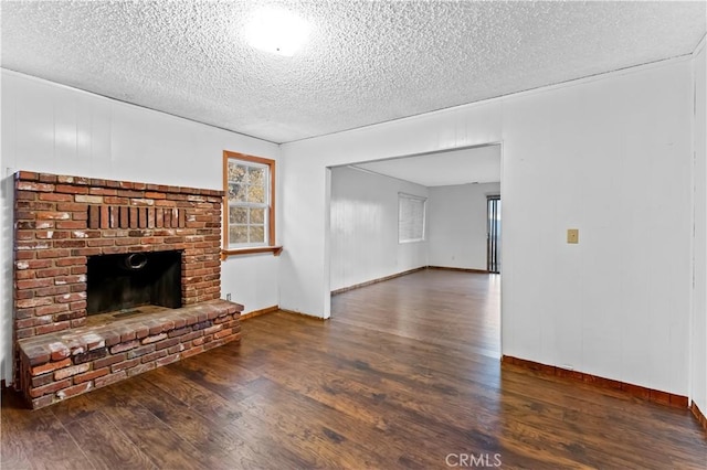 unfurnished living room featuring dark hardwood / wood-style floors, a fireplace, and a textured ceiling