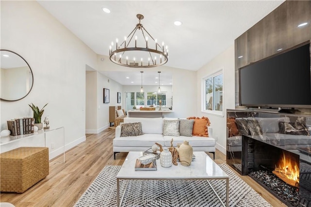 living room featuring a high end fireplace, a chandelier, and light hardwood / wood-style floors