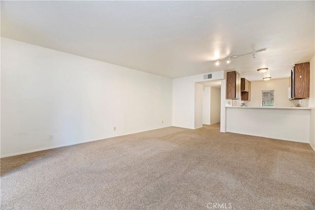 unfurnished living room featuring carpet flooring and rail lighting