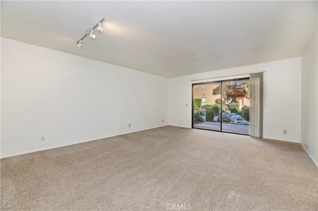 carpeted empty room featuring rail lighting