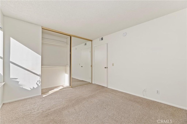 unfurnished bedroom with light carpet, a textured ceiling, and a closet