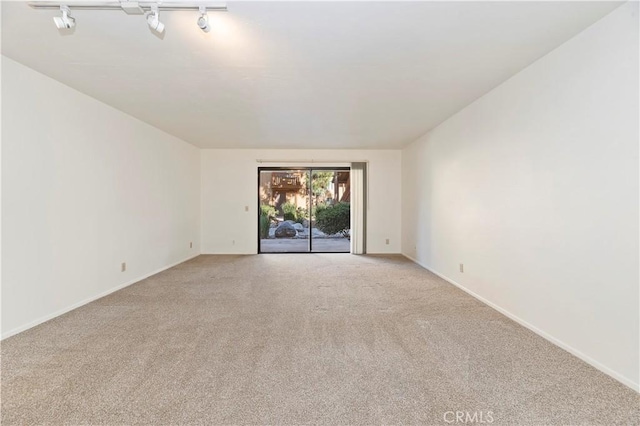 empty room featuring light carpet and rail lighting