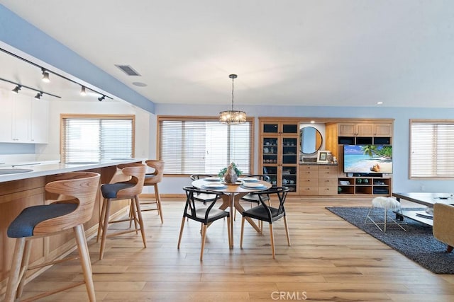 dining space with a notable chandelier and light hardwood / wood-style flooring