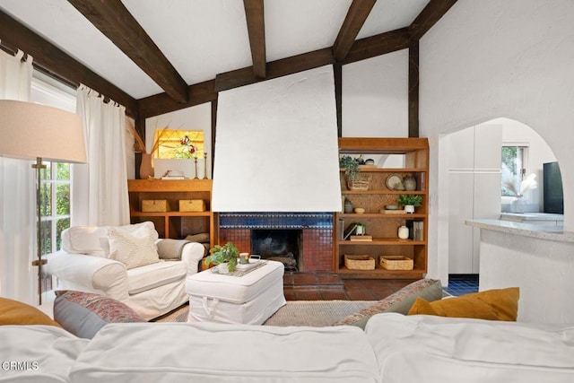 living room with vaulted ceiling with beams and a tiled fireplace