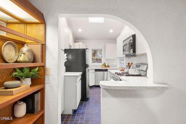 kitchen featuring stainless steel appliances, light countertops, ornamental molding, white cabinets, and dark tile patterned floors