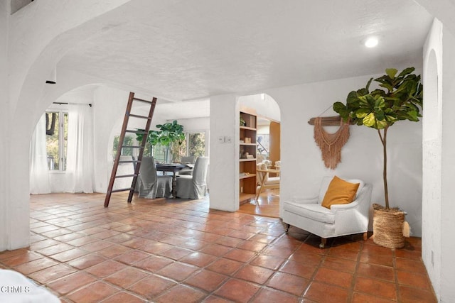 living area featuring arched walkways, tile patterned floors, and a healthy amount of sunlight