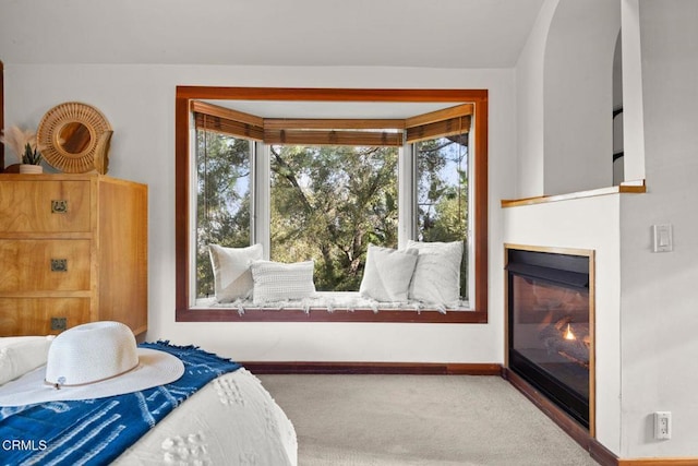 bedroom with carpet floors, baseboards, and a glass covered fireplace