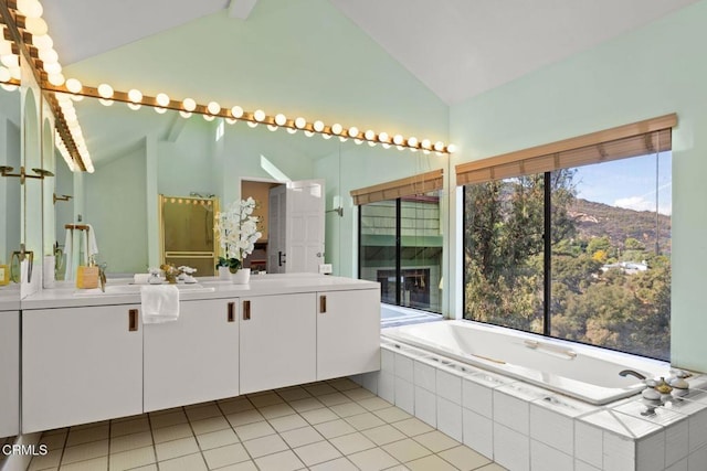 full bath with vaulted ceiling, double vanity, a sink, and a garden tub