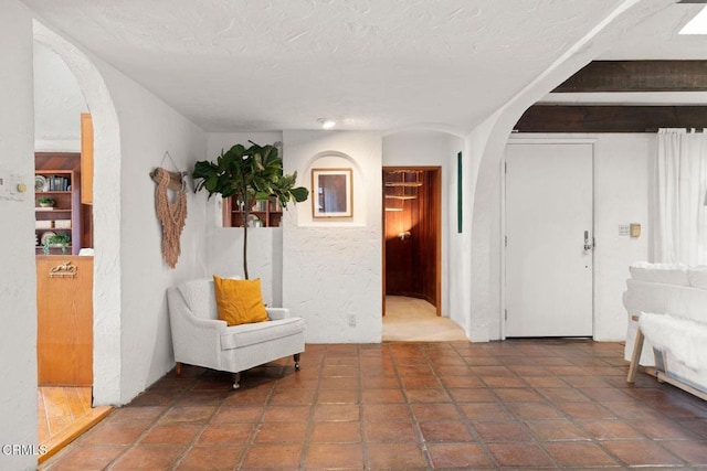 sitting room featuring arched walkways and a textured ceiling