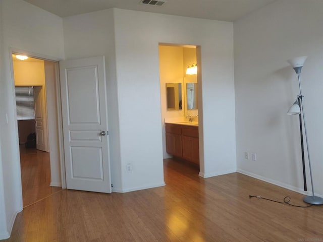 unfurnished bedroom with ensuite bath, sink, and light wood-type flooring