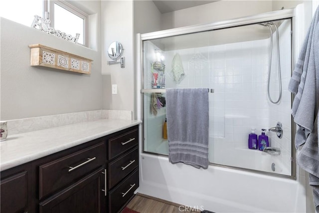 bathroom featuring hardwood / wood-style flooring, shower / bath combination with glass door, and vanity