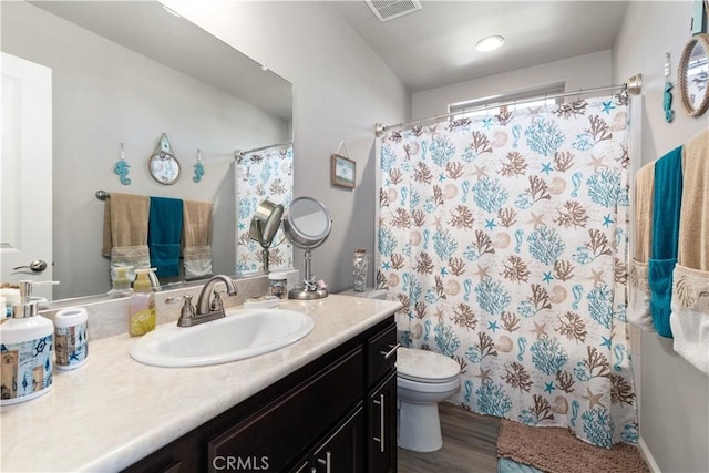 bathroom featuring hardwood / wood-style flooring, vanity, toilet, and walk in shower