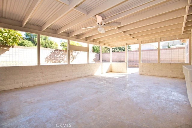 unfurnished sunroom featuring ceiling fan and a wealth of natural light