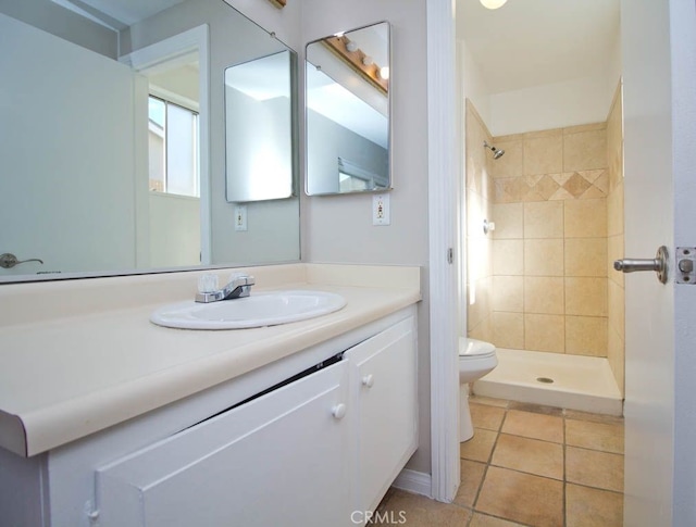 bathroom featuring a tile shower, tile patterned flooring, vanity, and toilet