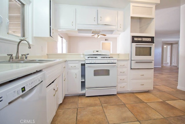 kitchen featuring white appliances, sink, ceiling fan, light tile patterned floors, and white cabinetry