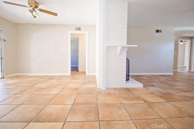 unfurnished living room featuring ceiling fan, a fireplace, and light tile patterned flooring