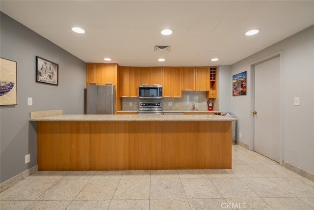 kitchen featuring kitchen peninsula, appliances with stainless steel finishes, decorative backsplash, and sink