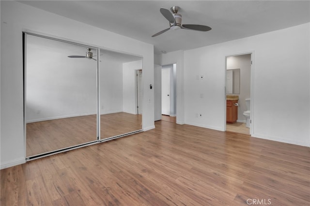 unfurnished bedroom with a closet, ensuite bathroom, light hardwood / wood-style floors, and ceiling fan