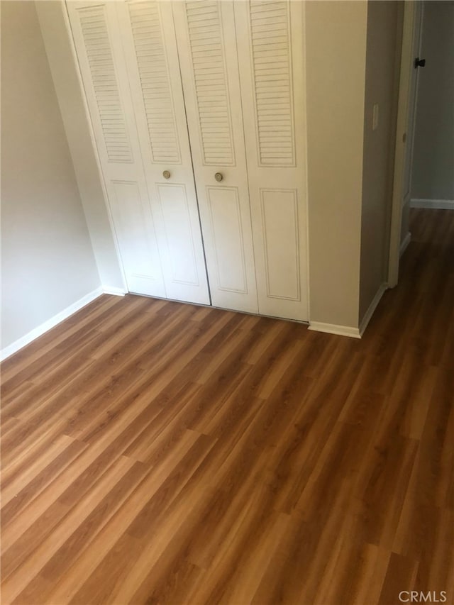 unfurnished bedroom featuring dark wood-type flooring and a closet