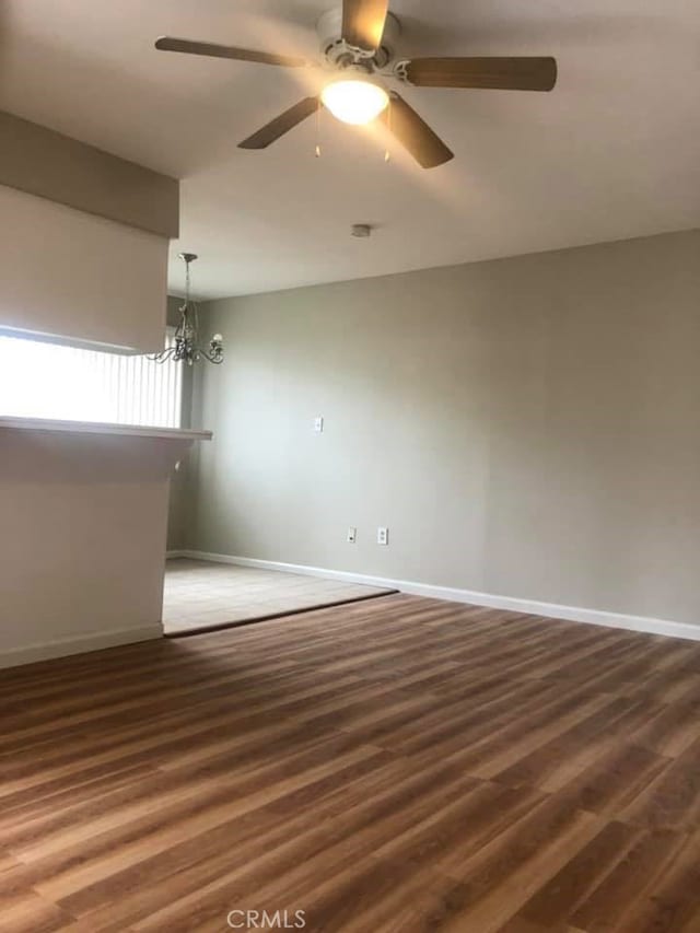 unfurnished room featuring dark hardwood / wood-style floors and ceiling fan with notable chandelier