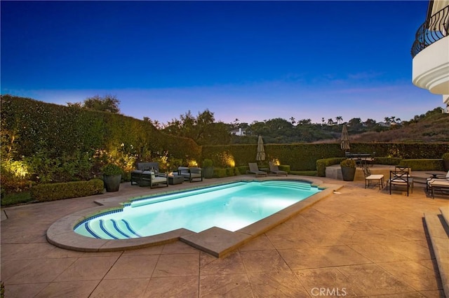 pool at dusk featuring an outdoor living space and a patio