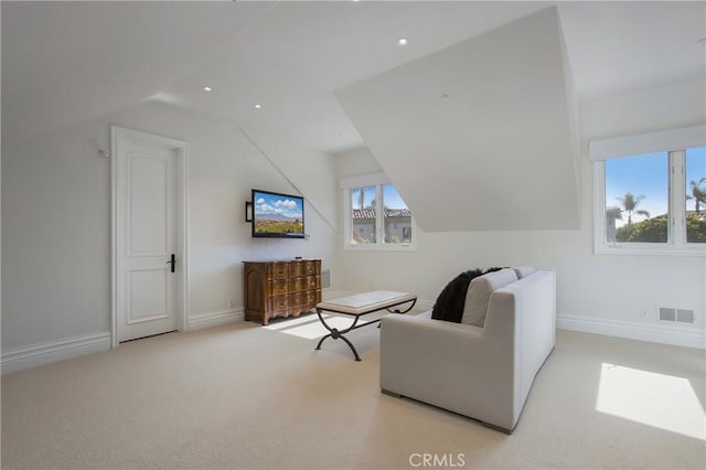 living area featuring plenty of natural light, light colored carpet, and lofted ceiling