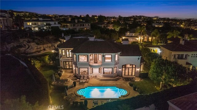 1 Moss Lndg, Laguna Niguel, CA 92677 - back of house at dusk with a balcony, a patio area, an outdoor pool, and stucco siding
