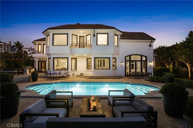 1 Moss Lndg, Laguna Niguel, CA 92677 - back of house at dusk with a balcony, an outdoor living space with a fire pit, french doors, and a patio area