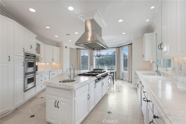 kitchen with island exhaust hood, a kitchen island with sink, sink, and appliances with stainless steel finishes